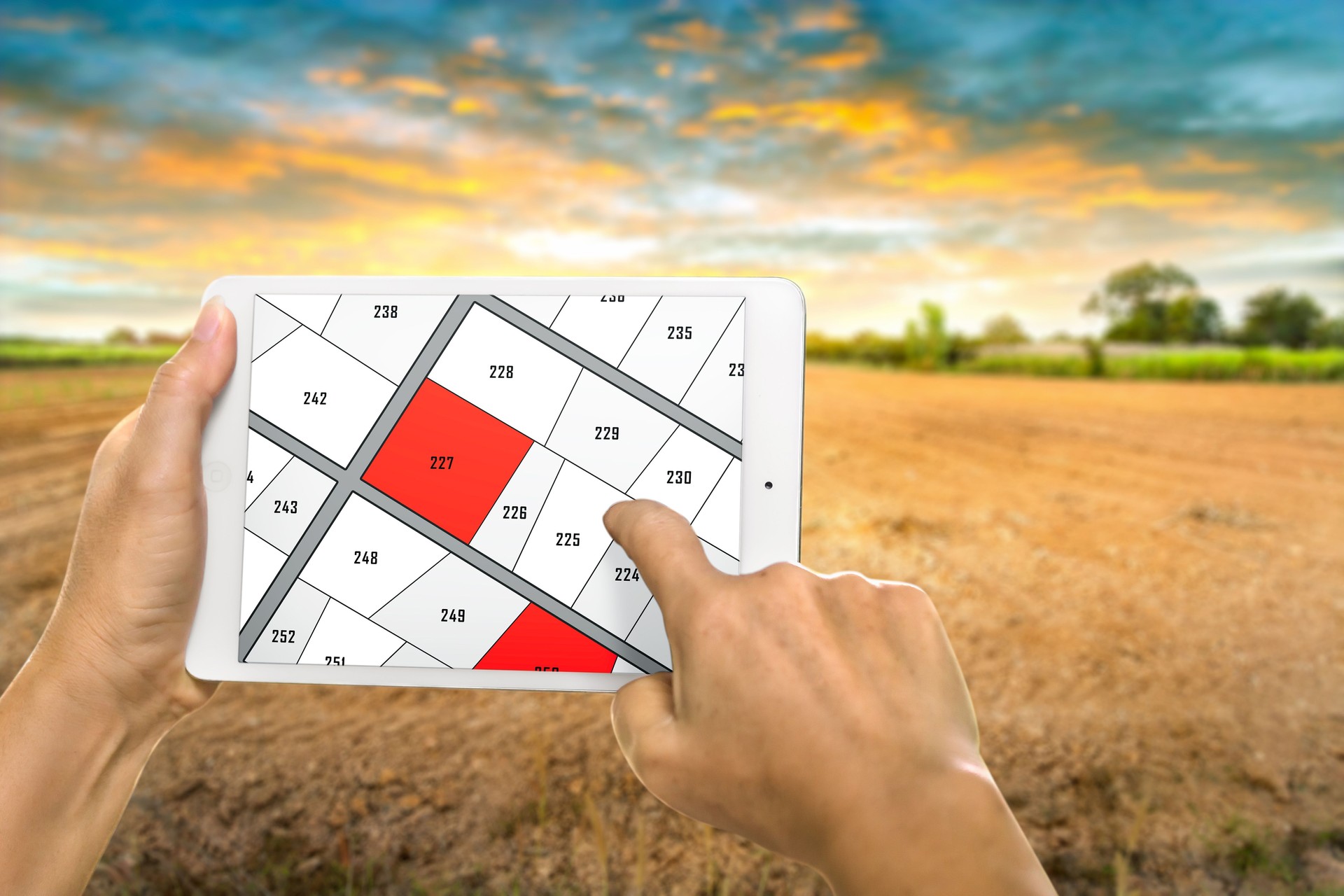 Man holding a tablet looking at lots of lands. Land plot management - real estate concept with vacant land for building construction and housing subdivision for sale, rent, buy, or investment.